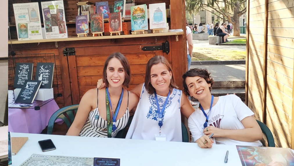 Fotografía en la que aparecemos Lola, María y yo, las tres autoras de Literup en una mesa delante del stand de la editorial